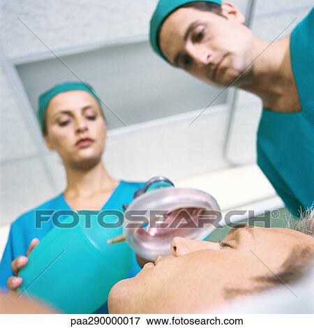 Doctors placing oxygen mask over patient's face View Large Photo Image Stock Photo - Doctors placing oxygen mask over patient's face. Fotosearch
