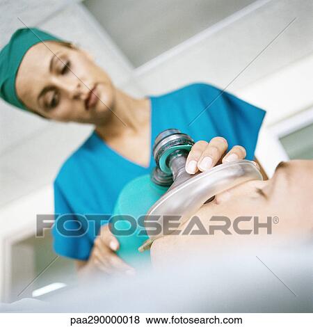 Female doctor holding oxygen mask over patient's face View Large Photo Image Stock Photo - Female doctor holding oxygen mask over patient's face. Fotosearch