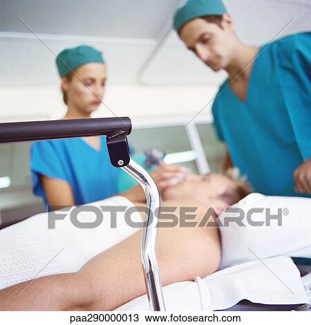 Stock Image - Interns standing over patient. Fotosearch