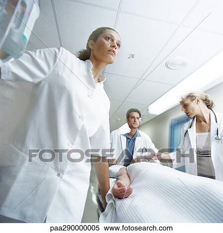 Stock Photography - Medical team pushing patient on gurney. Fotosearch