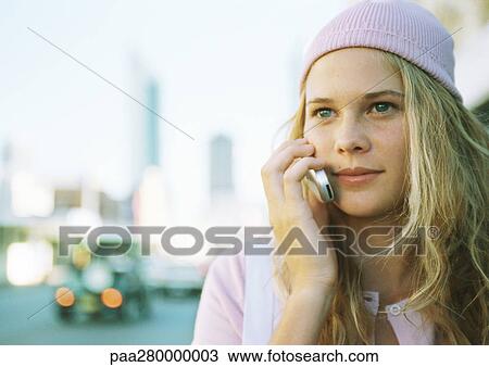 Stock Image - Teenage girl using cell phone in city. Fotosearch