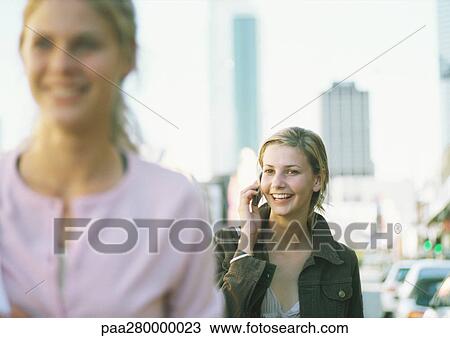 Two teenage girls in city setting, one using cell phone View Large Photo Image Stock Image - Two teenage girls in city setting, one using cell phone . Fotosearch
