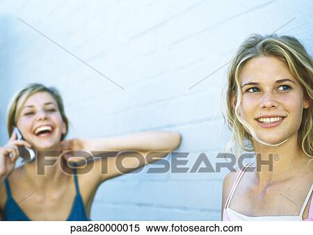 Two teenage girls, one using cell phone View Large Photo Image Stock Photography - Two teenage girls, one using cell phone. Fotosearch
