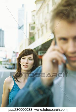 Young couple in city, man using cell phone View Large Photo Image Stock Image - Young couple in city, man using cell phone. Fotosearch