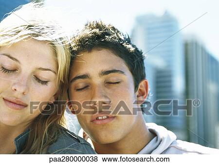 Young couple leaning heads together with eyes closed, portrait View Large Photo Image Stock Photo - Young couple leaning heads together with eyes closed, portrait. Fotosearch