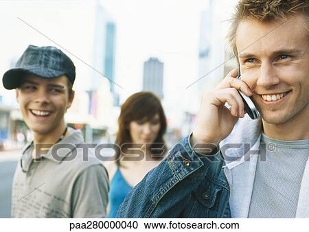 Young people in city setting, one young man using cell phone View Large Photo Image Stock Image - Young people in city setting, one young man using cell phone. Fotosearch
