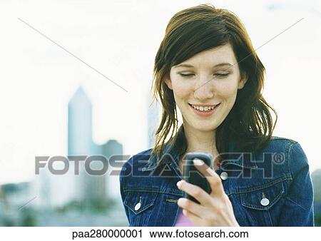 Stock Image - Young woman holding cell phone. Fotosearch