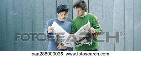 Two young men sharing newspaper View Large Photo Image Stock Photography - Two young men sharing newspaper. Fotosearch
