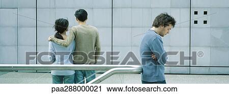 Young couple standing together while young man stands alone View Large Photo Image Stock Image - Young couple standing together while young man stands alone. Fotosearch