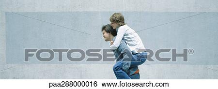Young man carrying young woman piggyback View Large Photo Image Stock Photograph - Young man carrying young woman piggyback. Fotosearch