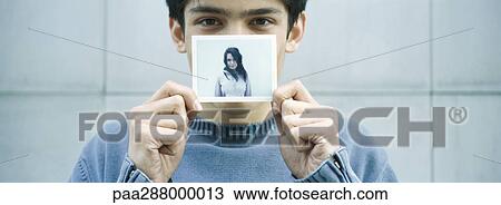 Young man holding up photo of young woman View Large Photo Image Stock Image - Young man holding up photo of young woman. Fotosearch
