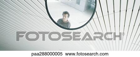 Stock Photography - Young man's reflection in mirror. Fotosearch