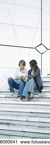 Young women sitting on steps, reading View Large Photo Image Stock Image - Young women sitting on steps, reading. Fotosearch