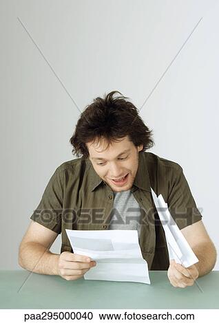 Young man looking at letter, smiling View Large Photo Image Stock Image - Young man looking at letter, smiling. Fotosearch