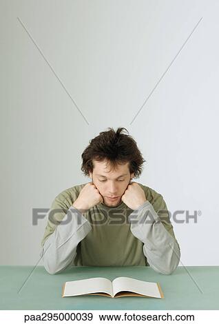 Young man looking down at notebook View Large Photo Image Stock Photo - Young man looking down at notebook. Fotosearch