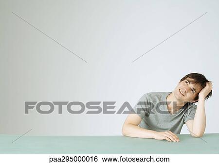 Stock Photograph - Young man looking up, portrait. Fotosearch