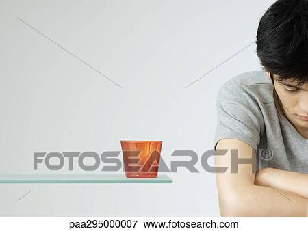 Stock Photo - Young man with arms folded and head down. Fotosearch