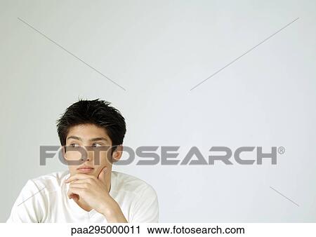 Young man with hand on chin, portrait View Large Photo Image Stock Image - Young man with hand on chin, portrait. Fotosearch