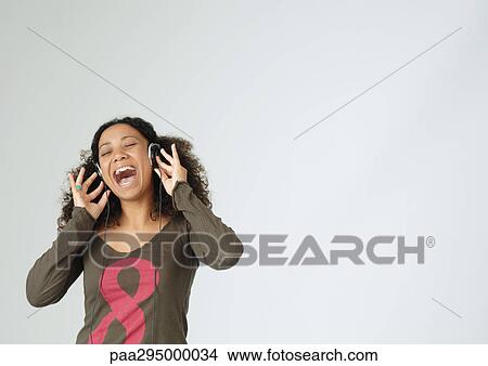 Young woman listening to headphones, singing, portrait View Large Photo Image Picture - Young woman listening to headphones, singing, portrait. Fotosearch
