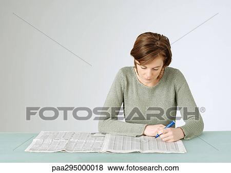 Young woman looking at open newspaper, holding pen View Large Photo Image Stock Photo - Young woman looking at open newspaper, holding pen. Fotosearch
