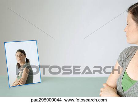 Young woman looking at self in mirror, portrait View Large Photo Image Picture - Young woman looking at self in mirror, portrait. Fotosearch