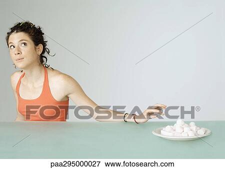 Young woman reaching toward plate of marshmallows View Large Photo Image Stock Photo - Young woman reaching toward plate of marshmallows. Fotosearch