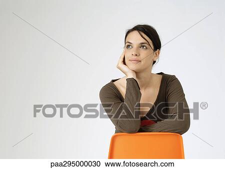 Young woman sitting backwards on chair, portrait View Large Photo Image Stock Image - Young woman sitting backwards on chair, portrait. Fotosearch