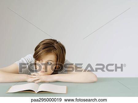 Young woman sitting with head on table next to open notebook View Large Photo Image Stock Photo - Young woman sitting with head on table next to open notebook. Fotosearch