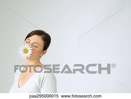 Young woman with flower in mouth and eyes closed, portrait View Large Photo Image Stock Photography - Young woman with flower in mouth and eyes closed, portrait. Fotosearch