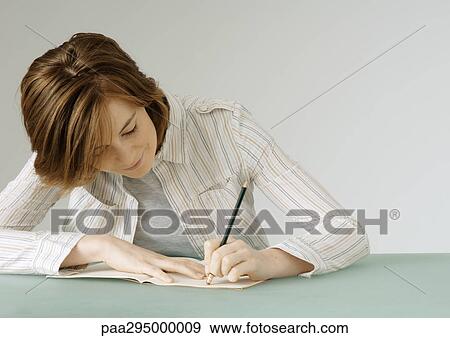 Stock Photo - Young woman with notebook, erasing. Fotosearch