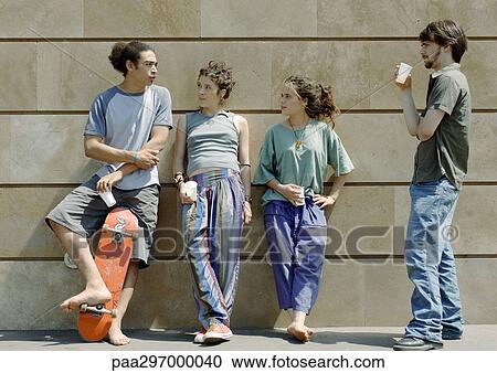 Four young friends standing, leaning against wall View Large Photo Image Stock Image - Four young friends standing, leaning against wall. Fotosearch