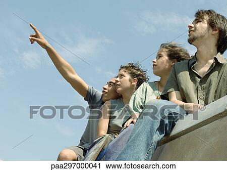 Four young friends standing, looking up at sky View Large Photo Image Stock Image - Four young friends standing, looking up at sky. Fotosearch