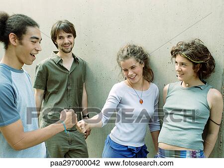 Four young friends standing next to wall, two touching fists View Large Photo Image Stock Image - Four young friends standing next to wall, two touching fists. Fotosearch