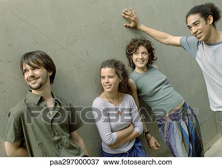 Four young friends standing next to wall View Large Photo Image Stock Photo - Four young friends standing next to wall. Fotosearch