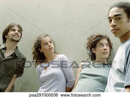 Four young friends standing next to wall View Large Photo Image Stock Photograph - Four young friends standing next to wall. Fotosearch