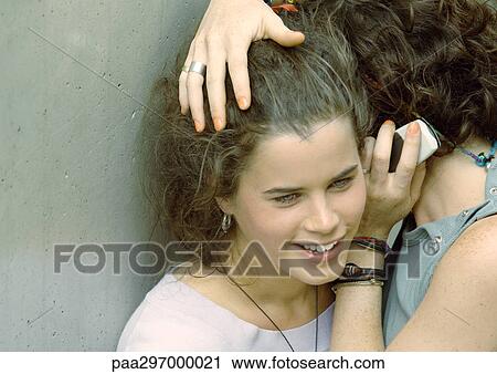 Two young women close together, listening to cell phone View Large Photo Image Stock Image - Two young women close together, listening to cell phone. Fotosearch