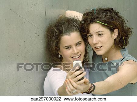 Two young women looking at camera phone View Large Photo Image Stock Image - Two young women looking at camera phone. Fotosearch