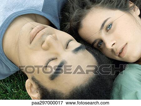 Young couple lying on grass together, close-up View Large Photo Image Stock Photo - Young couple lying on grass together, close-up. Fotosearch