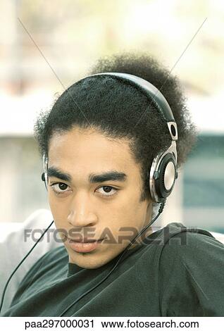 Young man listening to headphones, portrait View Large Photo Image Stock Image - Young man listening to headphones, portrait. Fotosearch