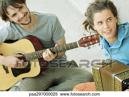 Young man playing guitar, young woman playing accordion View Large Photo Image Stock Photography - Young man playing guitar, young woman playing accordion. Fotosearch