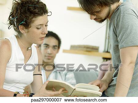 Young people looking at book together View Large Photo Image Stock Photo - Young people looking at book together. Fotosearch