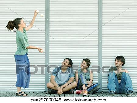 Young woman juggling while friends sit on ground watching View Large Photo Image Stock Photography - Young woman juggling while friends sit on ground watching. Fotosearch