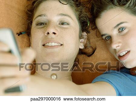 Young women looking at cell phone, close-up View Large Photo Image Stock Photograph - Young women looking at cell phone, close-up. Fotosearch