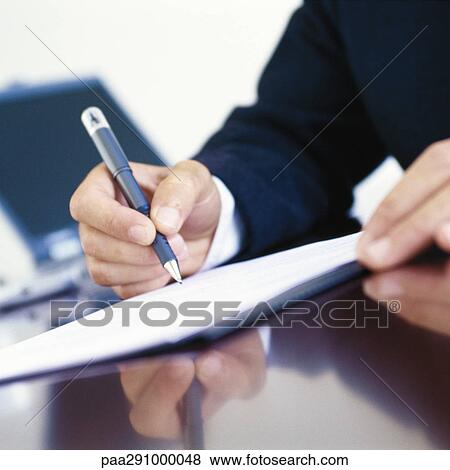 Stock Photo - Businessman signing document at desk, close-up of hands. Fotosearch