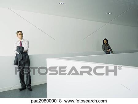 Businessman and businesswoman standing apart in office building View Large Photo Image Stock Photo - Businessman and businesswoman standing apart in office building. Fotosearch