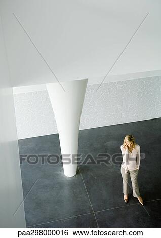 Stock Photograph - Businesswoman using cell phone in lobby, high angle view. Fotosearch
