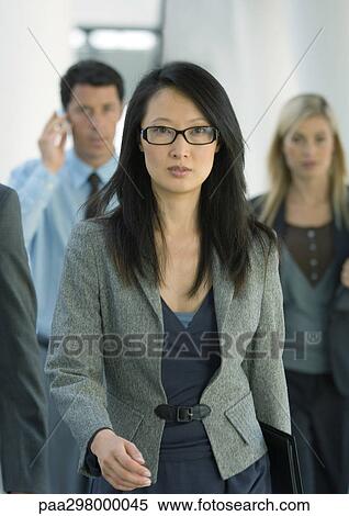 Businesswoman walking, colleagues behind her View Large Photo Image Stock Photography - Businesswoman walking, colleagues behind her. Fotosearch