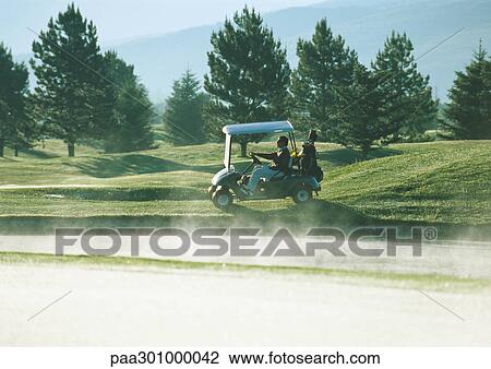 Golfer driving golf cart next to sand trap View Large Photo Image Stock Image - Golfer driving golf cart next to sand trap. Fotosearch