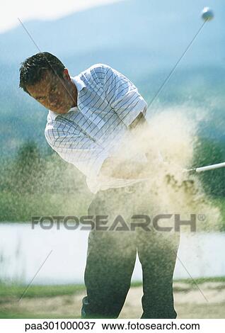 Golfer, mid-swing in sand trap, with sand in mid-air View Large Photo Image Stock Photo - Golfer, mid-swing in sand trap, with sand in mid-air. Fotosearch