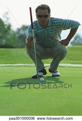 Golfer squatting on green, front view View Large Photo Image Stock Photograph - Golfer squatting on green, front view. Fotosearch